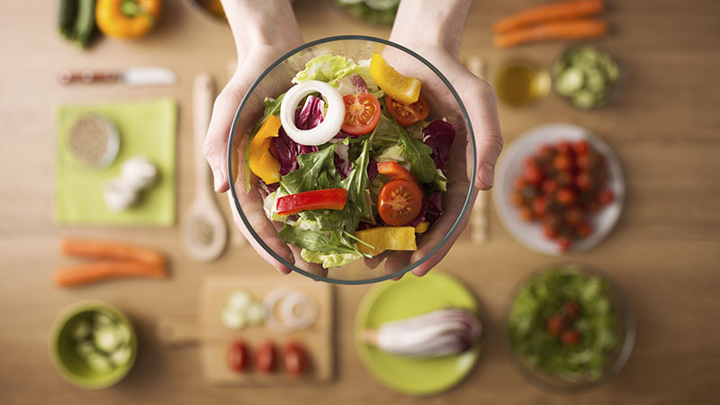 Uma mesa repleta de alimentos saudáveis com foco em uma salada