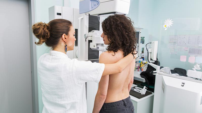 Profissional da saúde com mulher jovem fazendo exame de mamografia