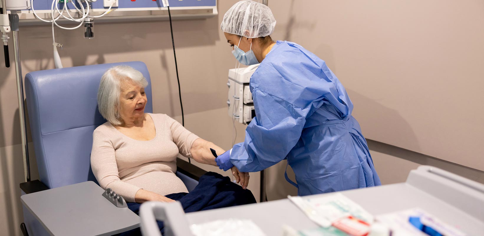 Enfermeira preparando uma paciente com câncer para sua quimioterapia no hospital