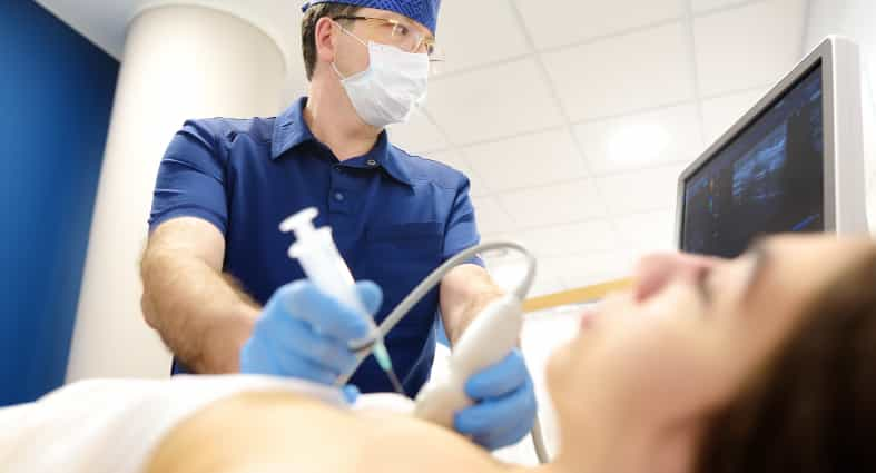 Médico preparando para punção em paciente deitada