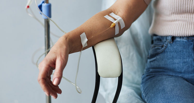 Mão feminina com infusão por gotejamento na sessão de tratament